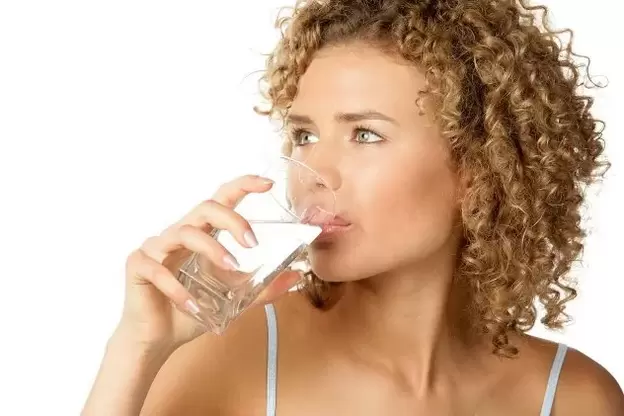 The girl follows a diet for lazy people, drinks a glass of water before eating